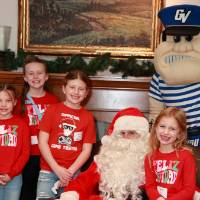 Four girls sitting with Santa & Louie at the Holiday Brunch.